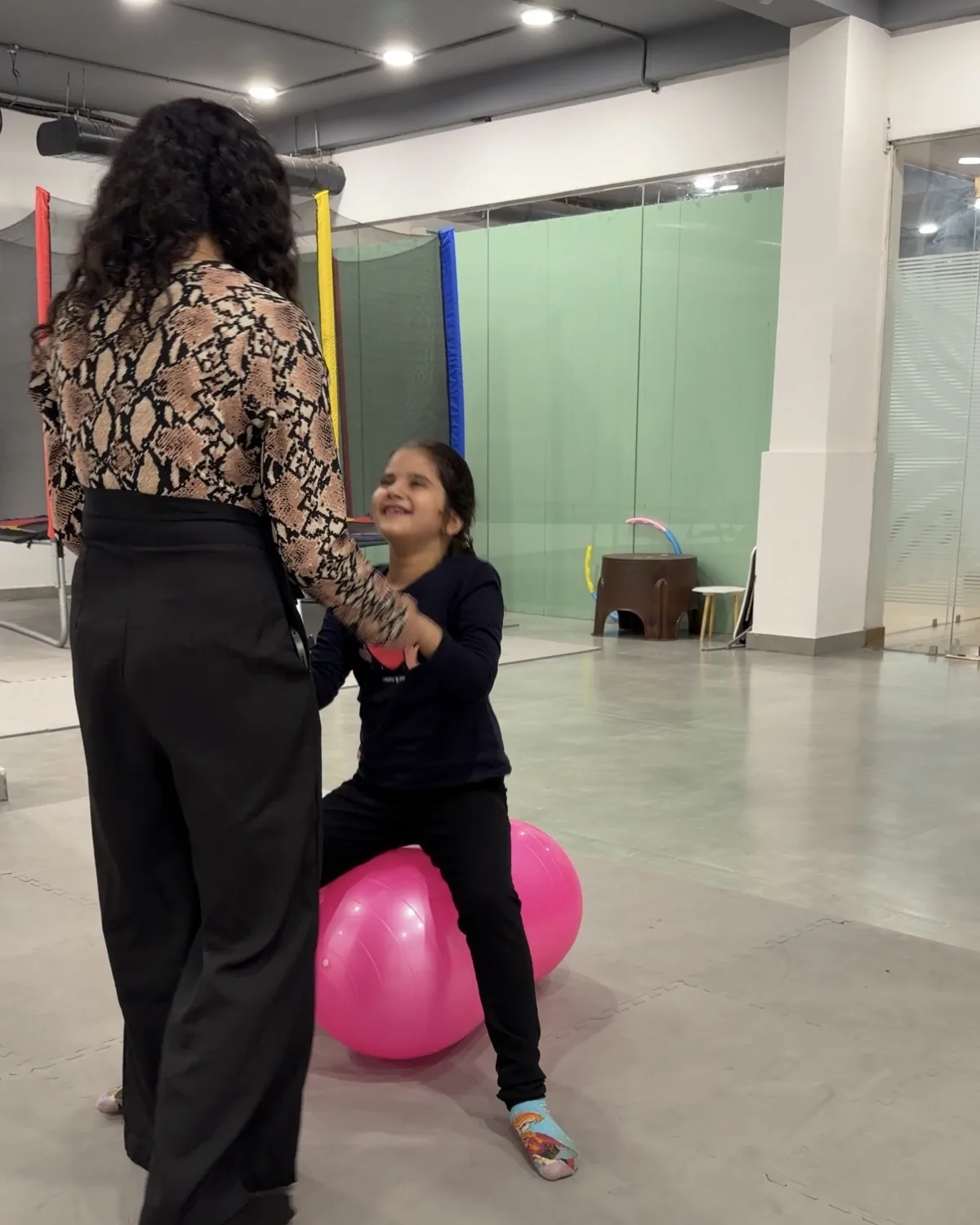 A therapist supporting a girl balancing on a therapy ball at Devine