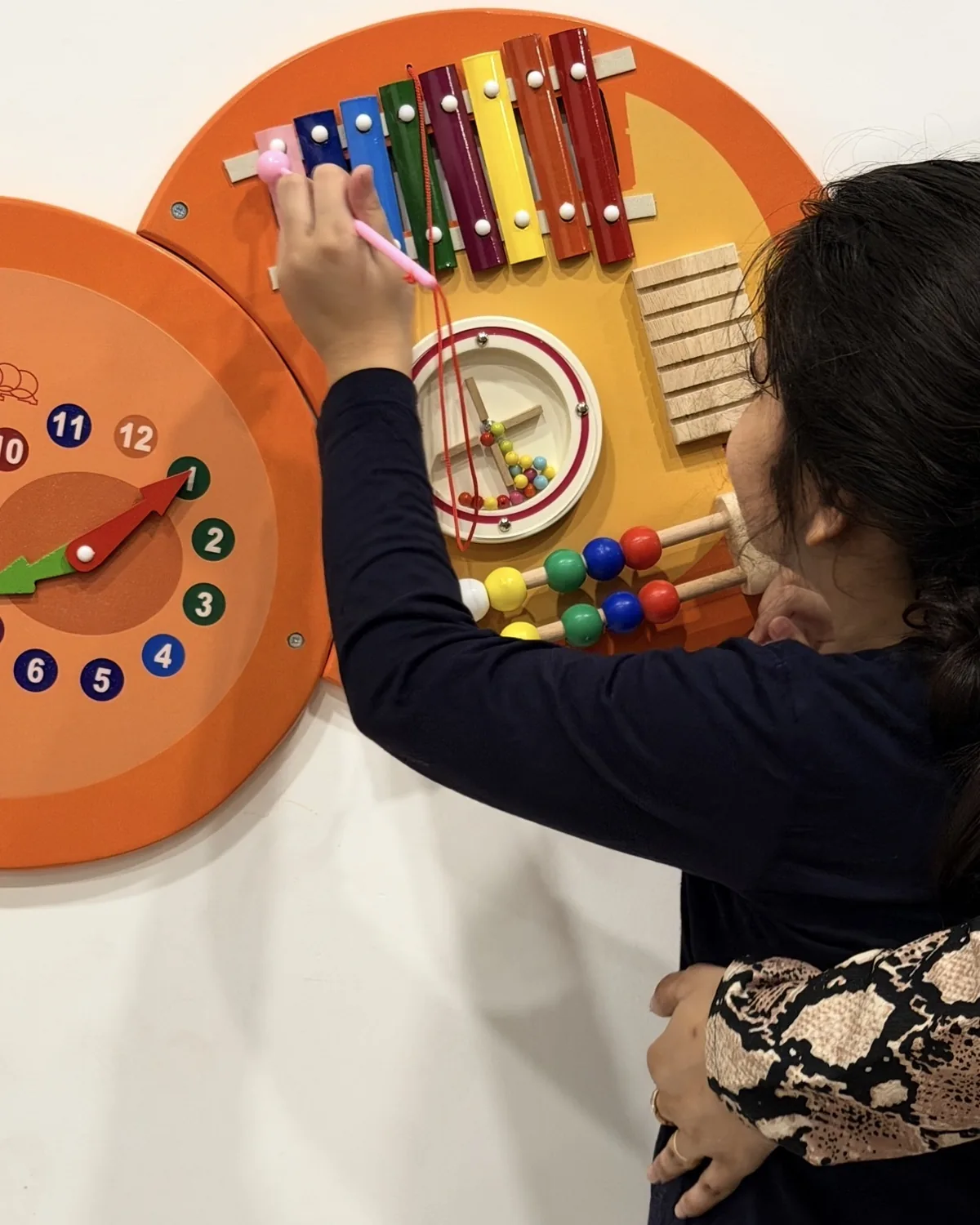 A child exploring an activity board with her therapist
