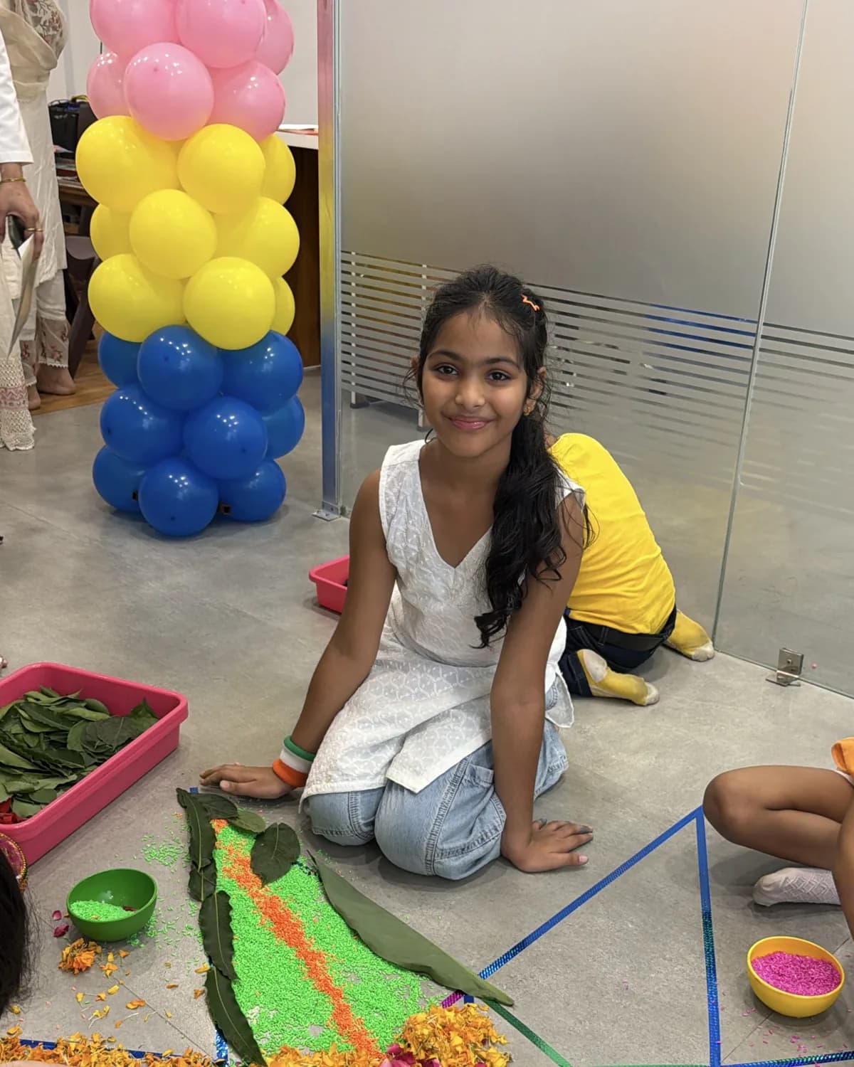 A girl smiling during a sensory rangoli activity at Devine